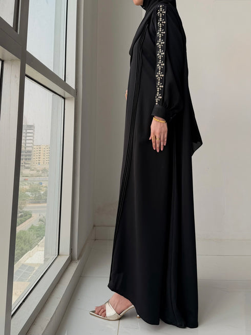 Woman wearing Haya Abaya paired with matching black chiffon hijab and gold accessories